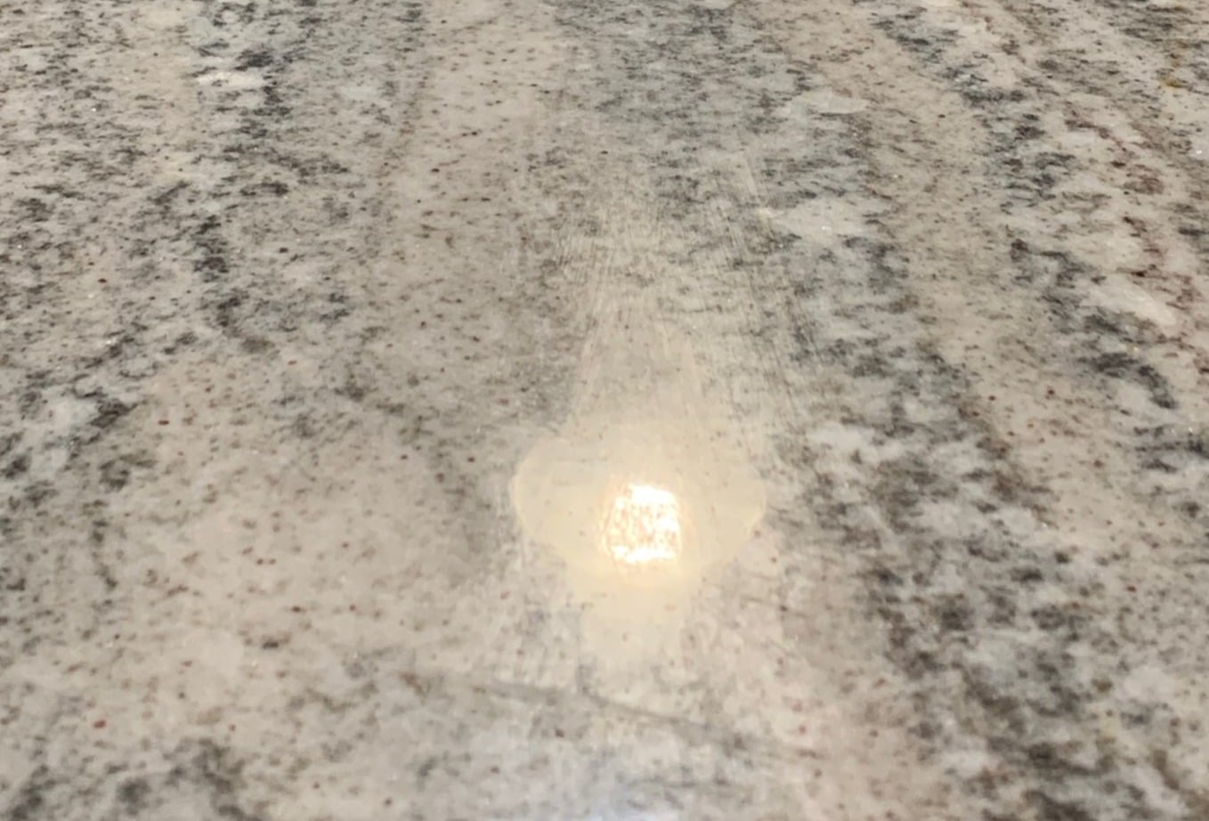 Close-up of cloudy streaks and scuffs caused by improper granite sealer.